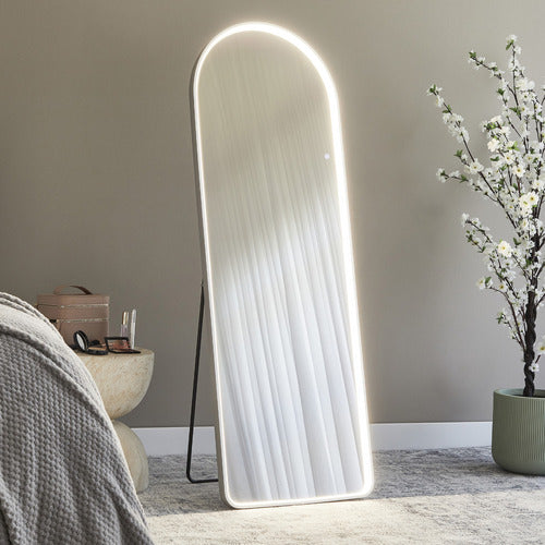 Modern floor mirror with LED lighting in a room setting with a plant and small table.