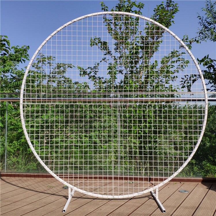 Round white grid screen on a wooden deck with trees in the background